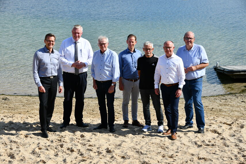 7 Personen vom Veranstalter-Team stehen im Sand am Godelheimer See.