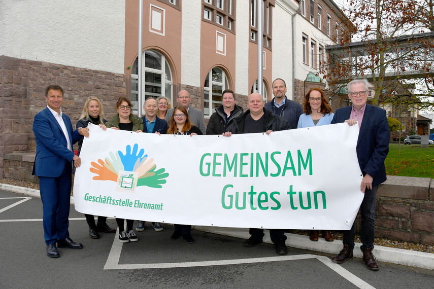 12 Personen halten vor dem Kreishaus einen Banner in den Händen mit der Aufschrift 'Gemeinsam Gutes tun'.